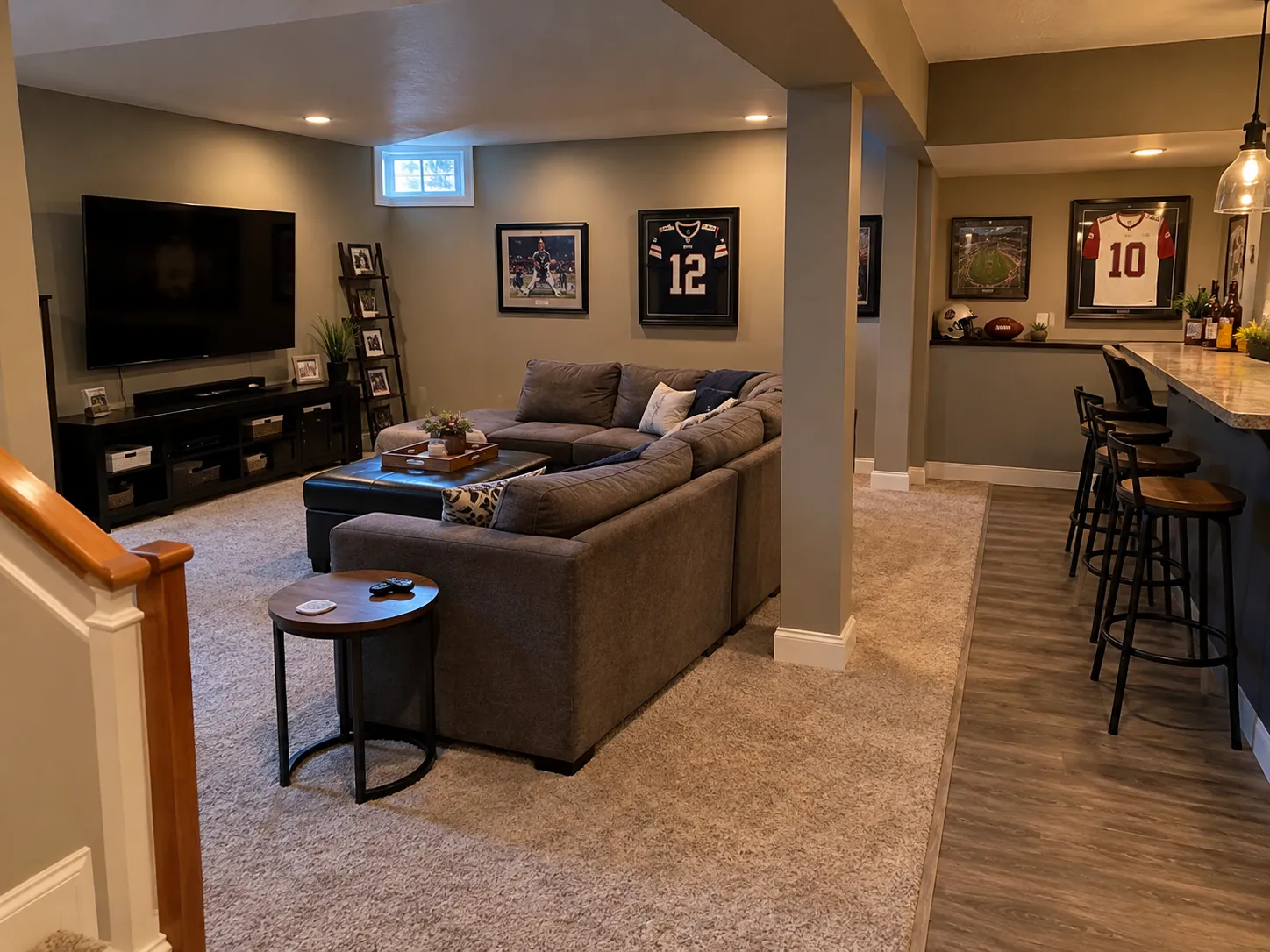 Basement sports lounge with framed jerseys, sectional sofa, TV and a bar with stools